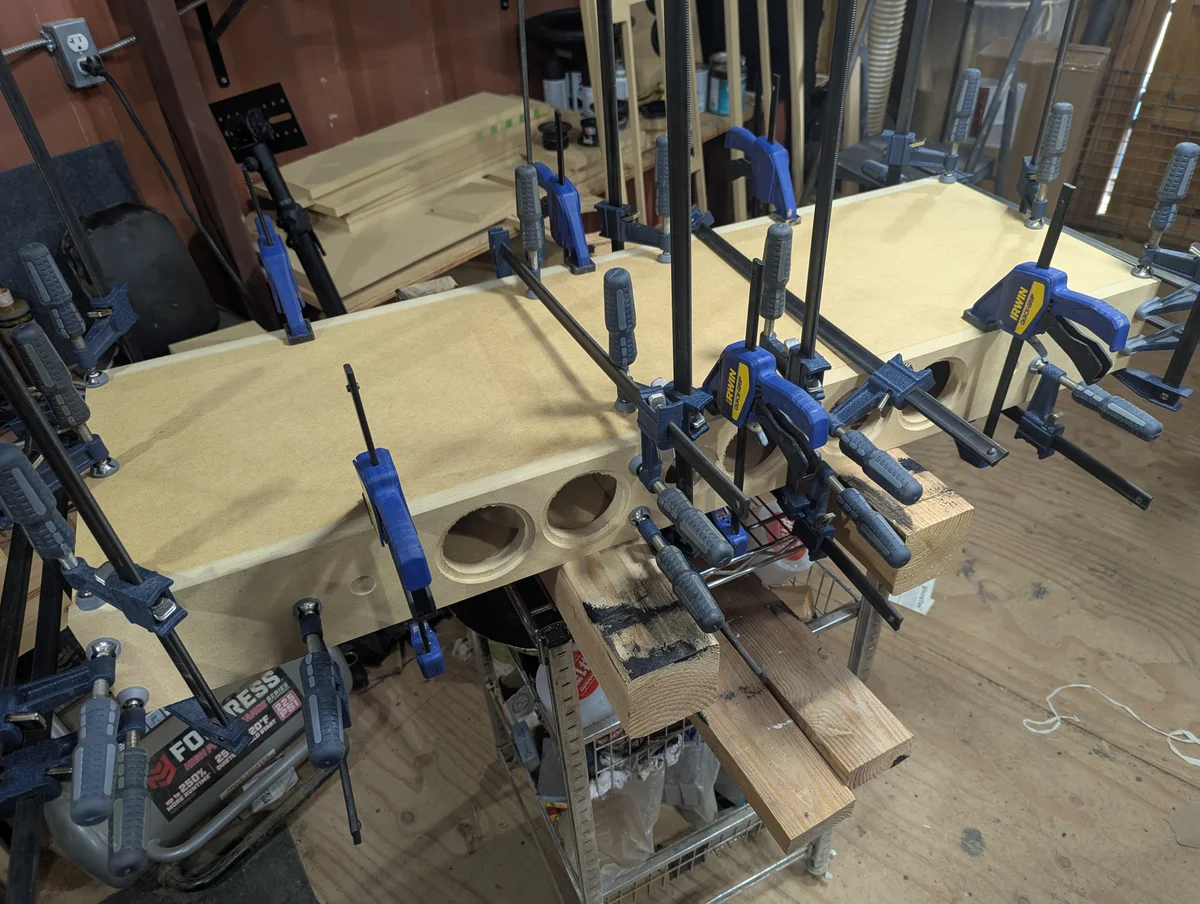 Bookshelf speaker cabinets being glued and clamped on workshop bench