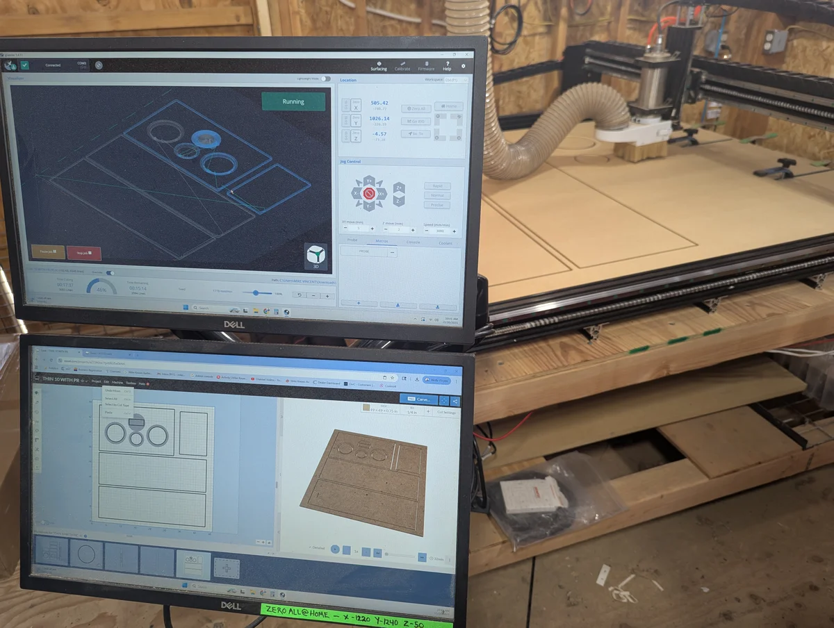 CAD speaker design on dual monitors with CNC router cutting cabinet panels in background