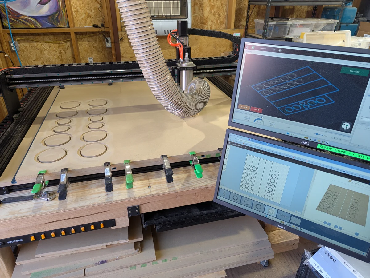 CNC router cutting speaker cabinet panels from CAD design with dual monitor setup in Arizona workshop