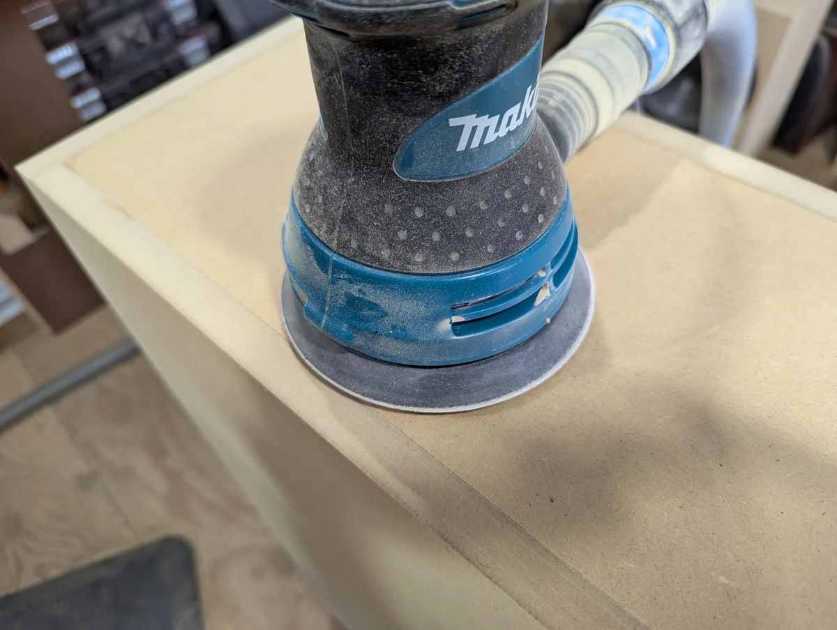 Speaker cabinet being sanded smooth before finish coating in workshop