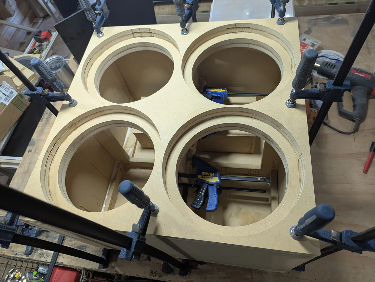 Quad subwoofer cabinet being assembled with clamps showing driver cutouts